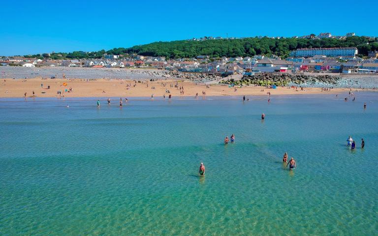 Westward Ho! beach arial photo looking back towards the village from the sea with people bathing in the sea