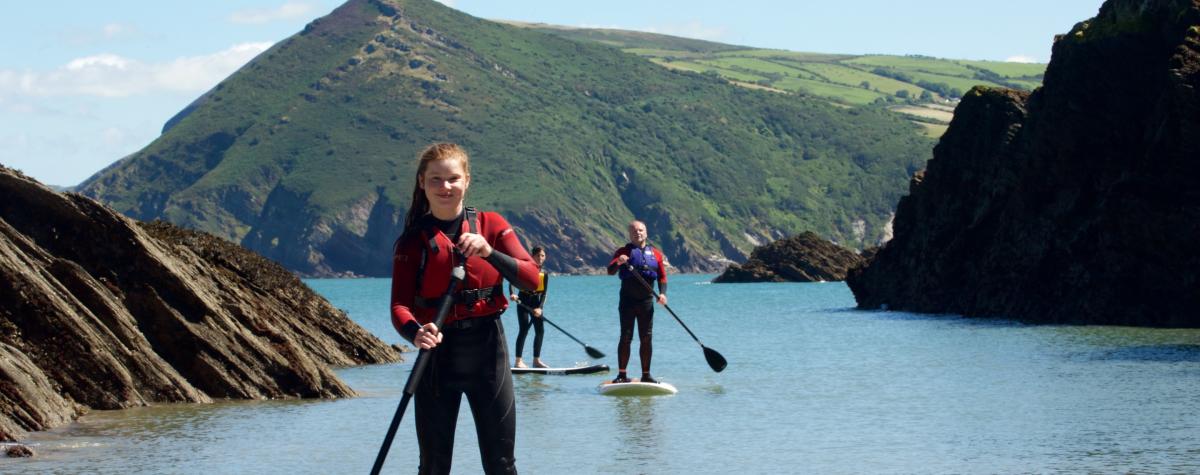 Three people on Stand-up-paddle boards in the sea near Watermouth, North Devon