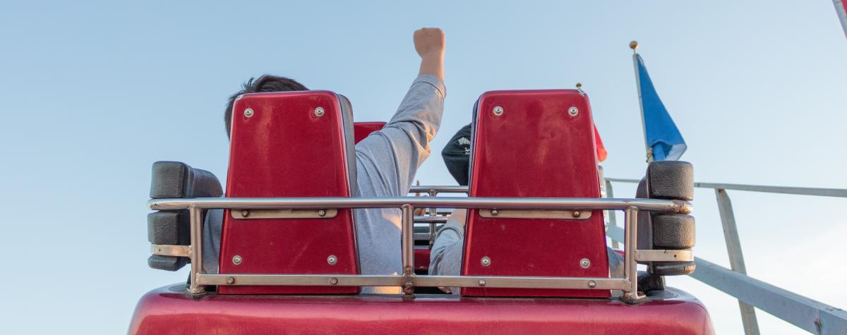 Two people sitting in a cart going up vertically on a rollacoaster