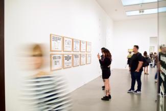 People looking at artworks on a wall in a gallery