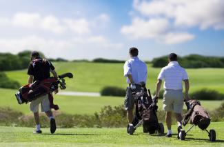 Three golfers on a golf course on a bright sunny day